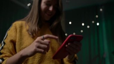 Cihazda Kadın El Cep Telefonu Denetimi Uygulaması Kullanılıyor. Yakın plan. Kırmızı Akıllı Telefonu Tutan Genç Kadın