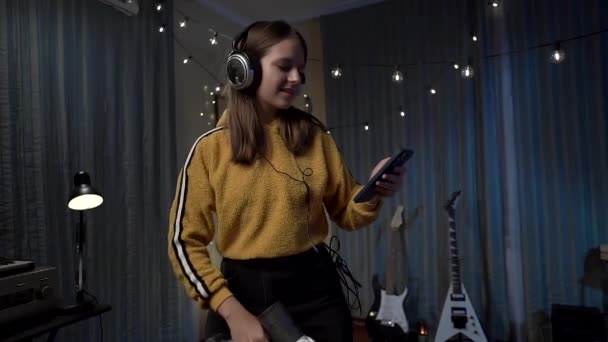 Egy Gyönyörű Lány Fülhallgatóban Aki Porszívó Szobát Takarítja Okostelefonra Néz — Stock videók