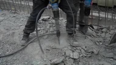 İki yol işçisi pnömatik bir matkapla eski asfaltı gevşetiyor. Köprü yenileniyor