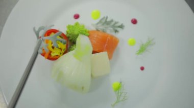 Aşçı malzemeleri tabağa koyar. Tabağın son hazırlığı. Sebzeler tabakta..