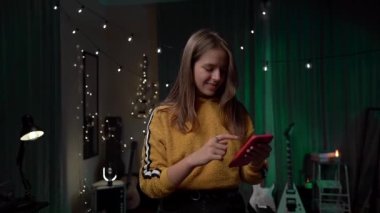 Cihazda Kadın Cep Telefonu Denetimi Uygulaması Kullanılıyor. Yakın plan. Kırmızı Akıllı Telefonu Tutan Genç Kadın