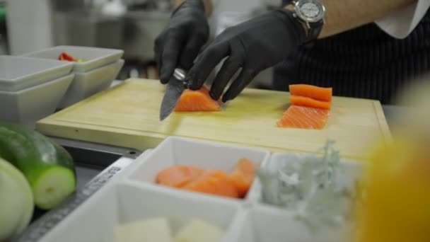 シェフナイフでボード上のサーモンをカットします シェフはサーモンを調理している シェフが鮭の切り身 — ストック動画