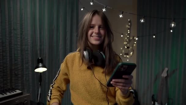 Retrato Chica Con Smartphone Auriculares Grandes Suéter Amarillo — Vídeos de Stock