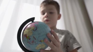 Globe 'lu Kid' e yakın çekim. Küçük çocuk küreye bakıyor. Çocuk coğrafya okuyor..
