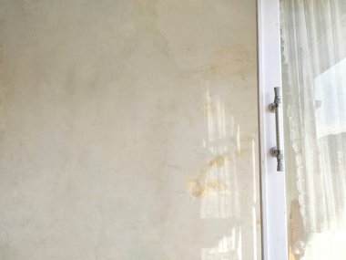 İç duvarda cam kapının yanında güneş ışığı yansıması ve sapı var..