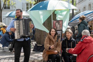 Paris, Fransa - 16 Mayıs 2023: Karikatür sanatçısı Montmarte, Paris 'te kadın yüzler çiziyor, sokak sanatçısı ve akordiyoncu. Pek çok sanatçı eserlerini bu çekici turistik bölgede mühürlemeye çalışır..