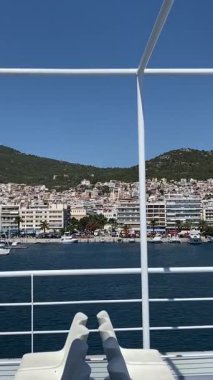 Feribottan, mavi gökyüzünden ve denizden Yunanistan 'ın Kavala kentinin manzarası. Popüler turizm merkezleri, seyahat temaları ve toplu taşıma araçları. Dikey video. Yüksek kaliteli FullHD görüntüler