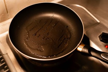 Zeytin ya da ayçiçeği yağı, metal elektrikli ocağın üzerinde, yapışmaz bir tavada parıldıyor. Yemek hazırlama, sağlıklı yemek pişirme ve mutfak kavramları için mükemmel..