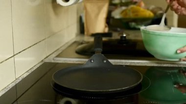 Bu yüksek kaliteli Full HD video çerçevesi, bir kadının bir kepçeden sıcak, yuvarlak bir tavaya ince bir krep hamuru dökerek sıvı hareketini ve ev yapımı pişirme sürecini yakaladığını gösteriyor..