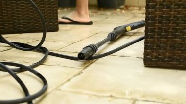 Bir adam terası su teçhizatıyla temizliyor. Kirli avluları, profesyonel basınçla yıkanan temiz yaşam alanlarına dönüştürmek. Ev servisi pazarlaması için ideal.