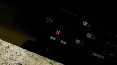 Parlayan H göstergesine sahip modern bir indüksiyon ocağının yakın çekim görüntüleri, kullanımdan sonra yüzeyin sıcak ve serinlediğini gösteriyor. Tam HD görüntüler.