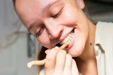 Bir kadının ağzında yanlış bir çubuk tutarak güldüğü samimi bir an. Fotoğraf, diş bakımına organik ve doğal bir yaklaşımla gerçek bir memnuniyet hissi veriyor..