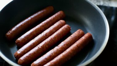 Tava ve sosislerin ısındığı, ev yapımı malzemelerin sergilendiği bir video. Mutfak dersleri, aile yemeği hazırlığı ya da sıcak yemek pişirme içeriği için ideal. Yüksek kaliteli klip.