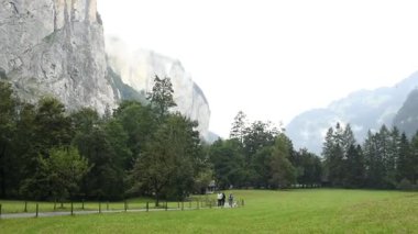 Captivating autumn landscape of Lauterbrunnen Valley Swiss Alps with a view of Trummelbach Falls entrance. Tourists enjoy nature amidst majestic mountains. FullHD footage.