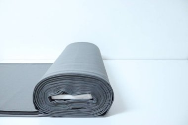 Beyaz stüdyo masasında gri kumaş cıvatanın yılan balığı yatay görüntüsü. Büyük bir yuvarlak gri perde kumaş mağazasının kesme yüzeyinde duruyor.