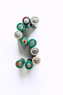 Beyaz arka planda aşınmış AA bataryaların üst görüntüsü. Elektronik atıkları, kirliliği ve acil çevresel sorunları temsil eden kavramsal görüntü.