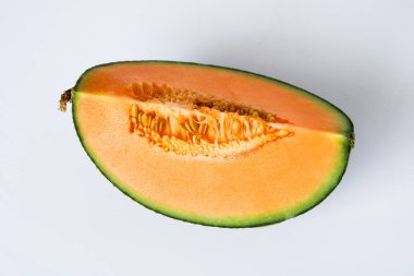Top view of a single wedge of ripe cantaloupe, showing the vibrant orange flesh and the small cluster of seeds, isolated on a white background.
