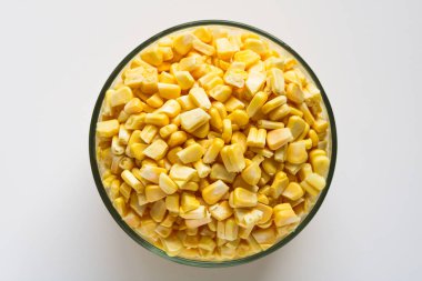 Top view of a clear glass bowl filled with fresh, bright yellow corn kernels, isolated on a white background.