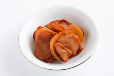 A view of a pile of dried Asam Gelugur or Asam Medan (Garcinia cambogia) slices on a white plate, a traditional sour fruit used in cooking.