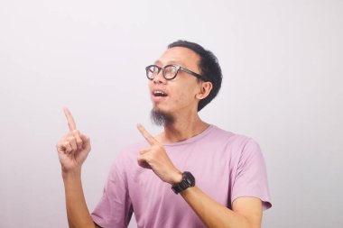 Orta yaşlı, gözlüklü Asyalı bir adam bu vahiy karşısında çok mutlu, yüzü çözümün farkına varılmasına şaşırmış, neşeli bir ifade ve yukarı doğru işaret eden bir parmak ile..