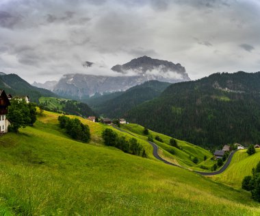 Dramatik bir yaz fırtınası Dolomite Alpleri 'ni silip süpürüyor ve yağmur manzarasını sırılsıklam ediyor. Sisli tepelerin ortasında, Chiesa di Santa Barbara zarif bir şekilde duruyor, İtalya 'nın kalbinde ebedi bir işaret.