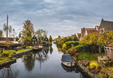 Hollanda, Giethoorn 'un sakin kanalları boyunca uzanan büyüleyici geleneksel Hollanda evi samanlı çatılar, canlı çiçek bahçeleri ve pitoresk ahşap köprüler ile süslenmiş.
