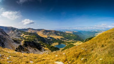 Romanya 'nın Parang Dağları' ndaki Galcescu Gölü yakınlarındaki vahşi Karpatlar 'da nefes kesici bir sonbahar günü yaşayın. Renklerin engebeli doruklarla buluştuğu Parang Dağları' nda.