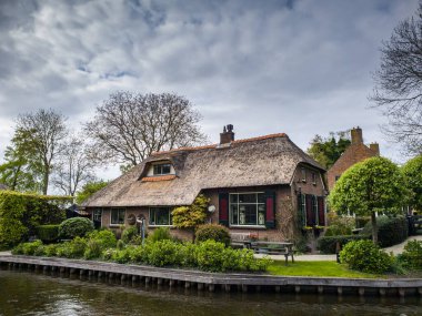 Hollanda, Giethoorn 'un sakin kanalları boyunca uzanan büyüleyici geleneksel Hollanda evi samanlı çatılar, canlı çiçek bahçeleri ve pitoresk ahşap köprüler ile süslenmiş.