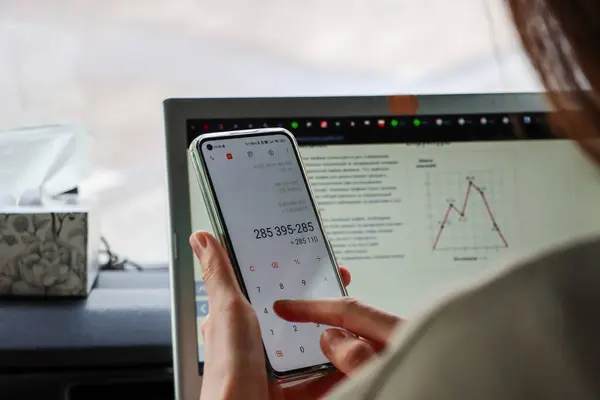 Kadın akıllı telefondan hesap makinesindeki harcamaları sayıyor. Yüksek kalite fotoğraf