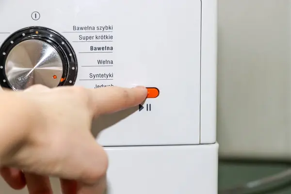 El çamaşır makinesinin düğmesine basar. Yüksek kalite fotoğraf