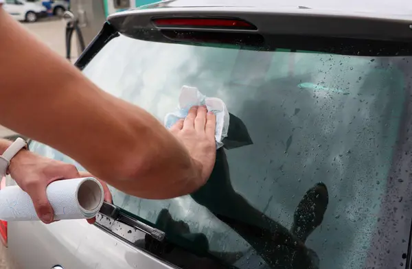 Adam arabanın camlarını siliyor. Yüksek kalite fotoğraf