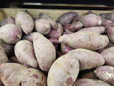 Markette tahta bir sandıkta taze mor tatlı patates yığını. 