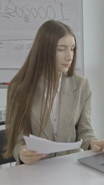 Genç bir profesyonel, düzgün bir ofis masasında bilgisayarla dokümanları inceliyor ve verimli bir çalışma sağlıyor..