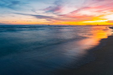 Resmin sol tarafında güneş batıyor. Mavi gökyüzü ile zıt ışıldayan altın turuncu dinlendirici bir tatil için sakin bir akşam deniz atmosferine demirlemiş pek çok gemi vardı..
