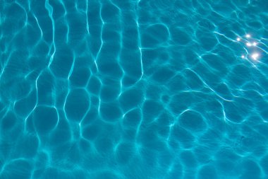 Parlak ışık yansımaları ve parlak yüzey renkleriyle mavi havuz suyu