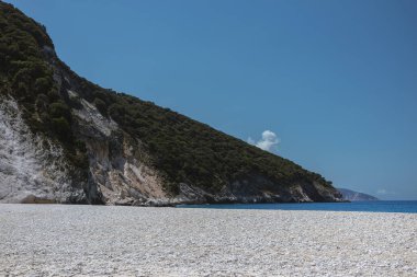 Akdeniz kıyısında kıvrılan kireçtaşı kayalıklarını gösteren geniş bir sahil manzarası var.