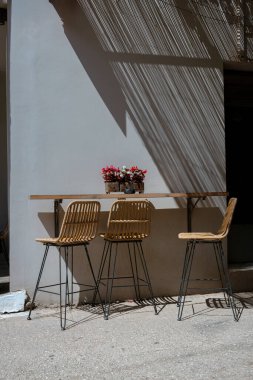 Hasır mobilyalar ve dekoratif gölgelerle Akdeniz terasında zarif bir açık hava yemek düzenlemesi.