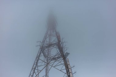 İletişim kulesi yukarıya doğru uzanıyor ve yoğun siste kayboluyor. Kaybolan nokta etkisi yaratıyor.