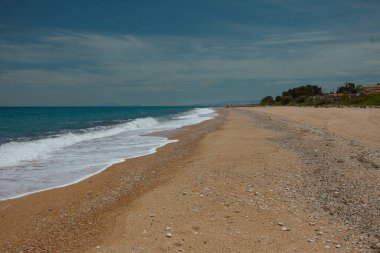 Geniş kumlu sahil, yumuşak dalgalar Akdeniz 'de kıyı ve kıyı bitkileriyle buluşuyor.