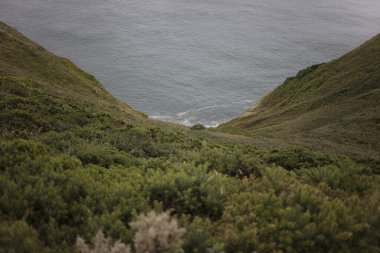 Yeşil kıyı kayalıkları arasındaki doğal vadi aşağıdaki deniz manzarasını gözler önüne seriyor. Dramatik uçurum oluşumları ve okyanus manzaralı İrlanda kıyıları.