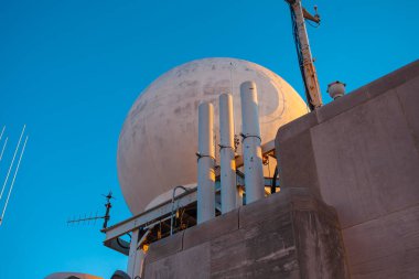 Beyaz kubbe radar sistemi ve donanma gemisindeki iletişim ekipmanları mavi gökyüzü arka planına karşı