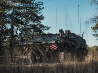 Zırhlı personel taşıyıcı, uzun çim tarlasına yerleştirilmiş, birden fazla anten ve iletişim ekipmanı var.