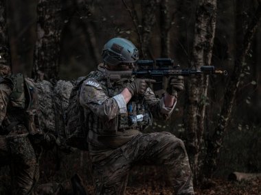 Ormandaki atış talimi sırasında optik dürbünlü tüfeği hedef alan asker.