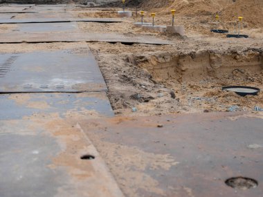 İnşaat alanı genel görünümü, arka planda kazılmış alanla birlikte beton temel levhaları ve inşaat ekipmanlarını gösteriyor.