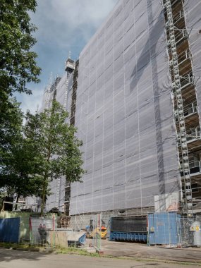 Geniş yapı iskelesi ve çit bariyerleri olan büyük bir inşaat alanı.