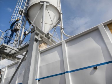 Tarım işçisi, çiftlik hayvanları beslenme işlemleri için silo ekipmanlarıyla mobil besleme kamyonu kullanıyor.