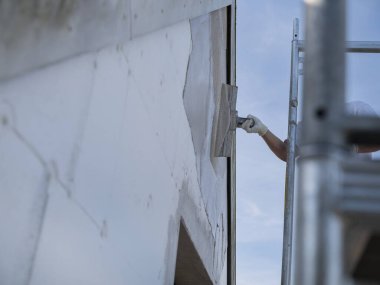 İnşaat işçisi bina yenileme projesi sırasında dış duvara şekil veya alçı uygulamak için mala kullanıyor