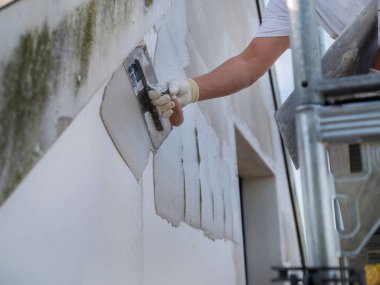 Tadilat sırasında profesyonel mala tekniğini kullanarak duvarlara alçı yapıştıran inşaat işçisi.