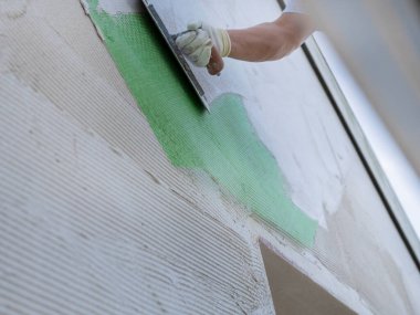 İnşaat işçisi yenileme ve güçlendirme çalışmaları sırasında duvar yüzeyine takviye ağ uyguluyor.