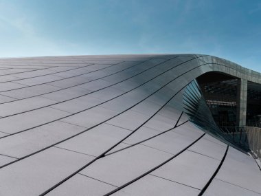 Eğri metalik bina cephesinin yakın plan detayları panel eklemlerini ve akan mimari çizgileri gösteriyor